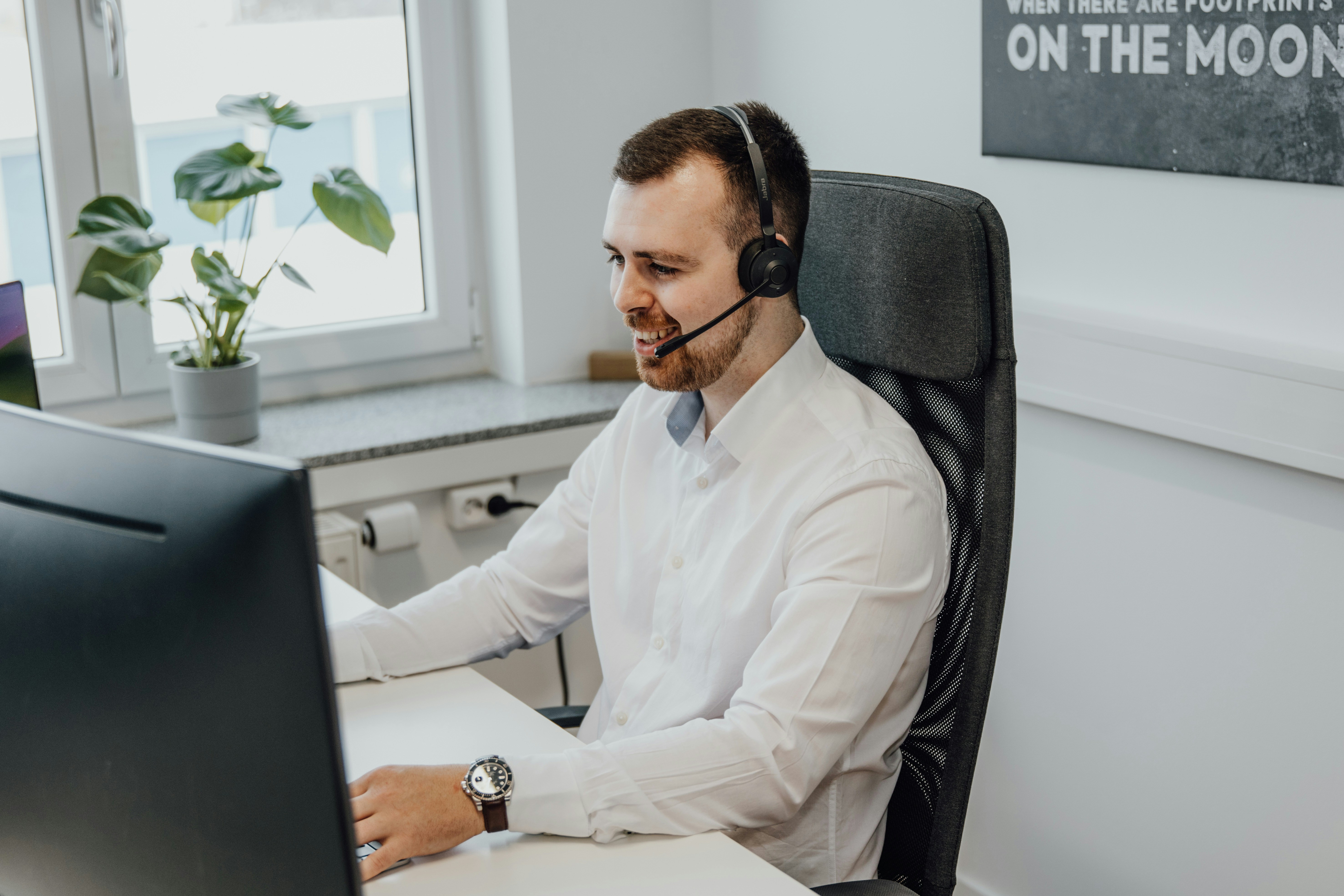 a person in a office awnsering the phone with his computer